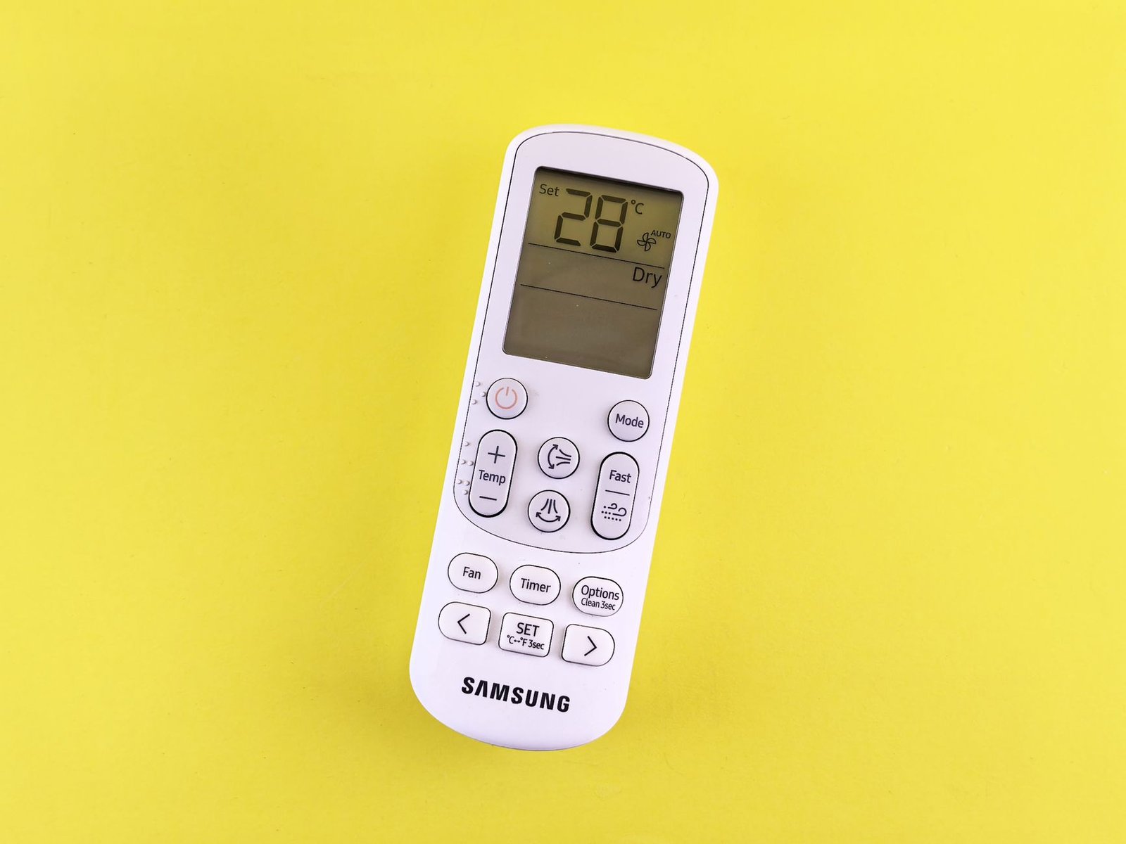 A backlit universal AC remote control sitting on a modern living room table.