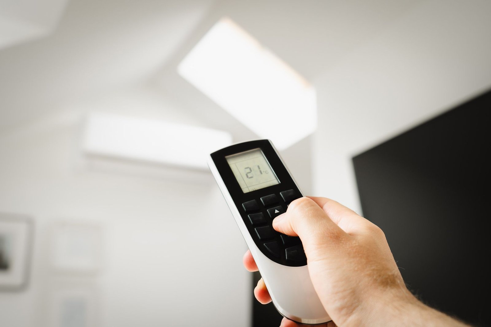 A modern learning thermostat mounted on a living room wall for efficient central air conditioning.
